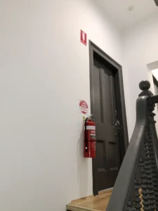 Supreme Fire Solutions Fire Extinguisher next to a door with the fire extinguisher signage above.